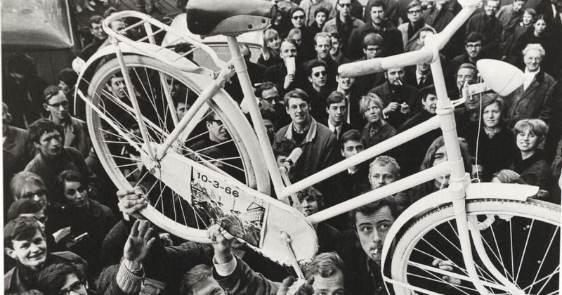 Provos met een witte fiets. Beeld Still uit de Vara-film Rebelse stad Provo in Amsterdam Provos met een witte fiets. Beeld Still uit de Vara-film Rebelse stad Provo in Amsterdam